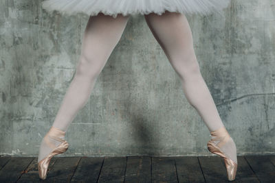 Low section of woman in ballet shoe dancing on floorboard