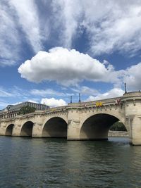 Arch bridge over river against cloudy sky