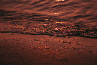Water on shore at beach during sunset