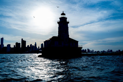 Lighthouse by sea against sky