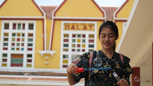 Woman holding bubble wand against building