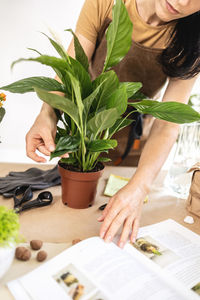 Female gardener studying gardening book at workshop transplantation houseplants