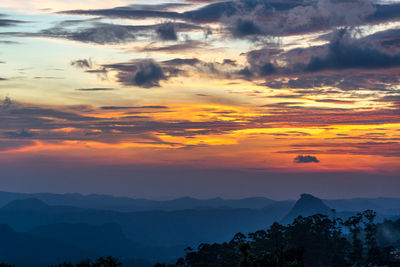 Scenic view of dramatic sky over silhouette landscape during sunset