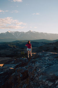 Rear view of man standing on mountain against sky