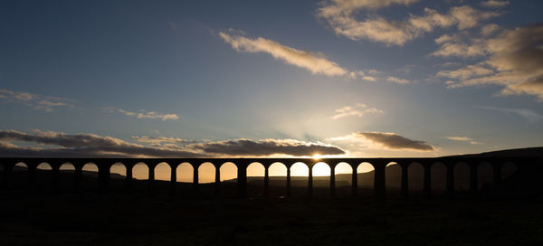 Silhouette bridge against sky during sunset