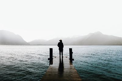 Man standing on lake against clear sky