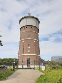 Low angle view of lighthouse by building against sky