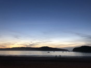 Scenic view of beach against sky at sunset