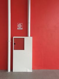 Box and pipe against red wall