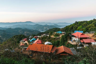 Houses by trees and mountains against sky