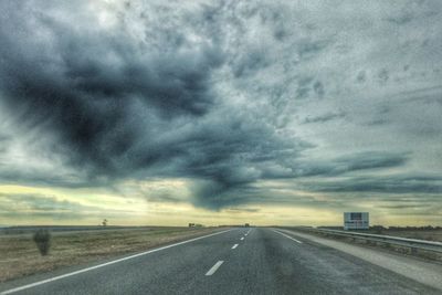 Country road against cloudy sky