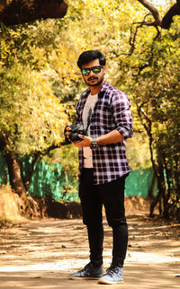 Full length portrait of young man standing in sunglasses