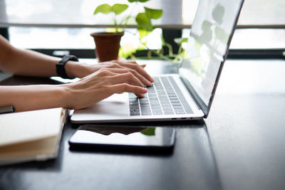 Midsection of man using laptop on table