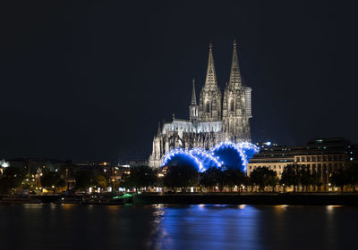 Illuminated buildings by river at night