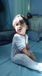 Cute girl sitting on bed at home