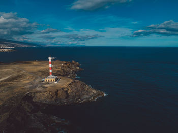 Lighthouse by sea against sky