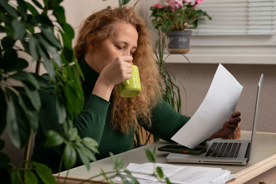 Young woman using mobile phone at table