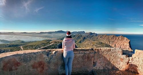Rear view of man standing on mountain against sky