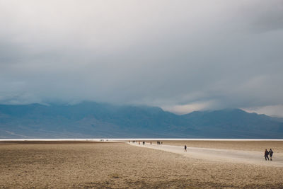 Scenic view of arid landscape against cloudy sky