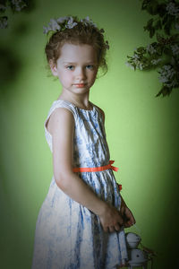 Portrait of girl wearing flowers while standing against wall