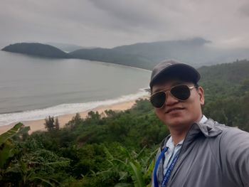 Portrait of young man looking at mountains against sky