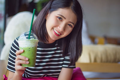 Portrait of smiling young woman holding drink