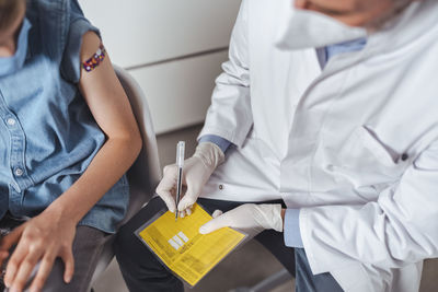 Doctor filling immunization certificate with boy at vaccination center