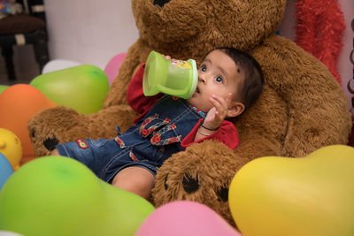 Portrait of baby girl with toy on bed at home