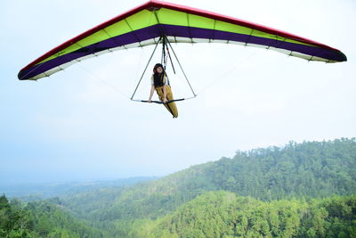 Low angle view of girl paragliding against sky