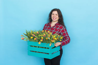 Portrait of a smiling young woman against blue background