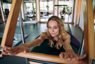 Portrait of smiling young woman sitting on railing