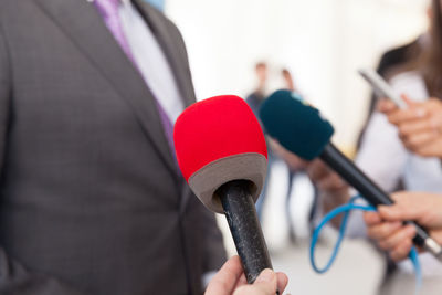 Midsection of businessman standing by microphones