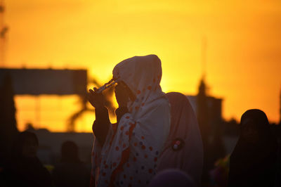 Rear view of silhouette woman photographing at sunset