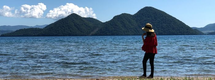 Woman standing in sea against mountains