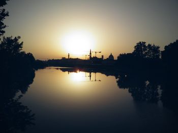 Reflection of trees in water at sunset