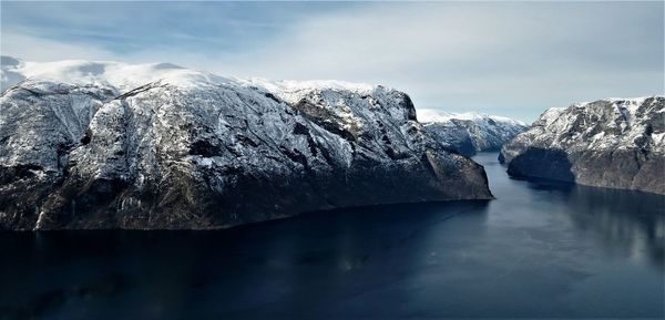 Aerial view of snowcapped mountains by lake against sky