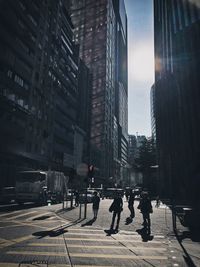 Silhouette people on sidewalk amidst buildings in city