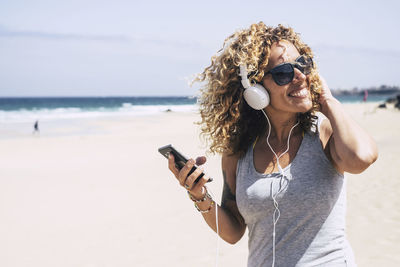 Woman listening to music through headphones at beach