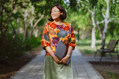 Portrait of woman standing on footpath