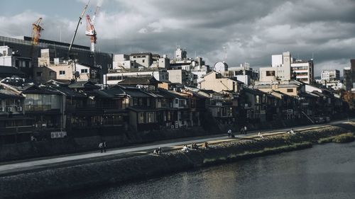 Buildings by river against sky in city