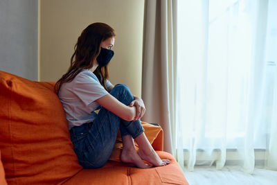 Young woman sitting on bed at home