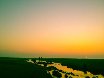 Scenic view of agricultural field against clear sky at sunset