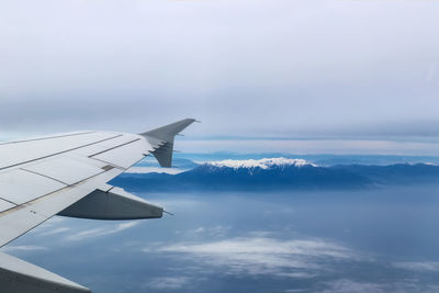 Airplane flying over mountains against sky