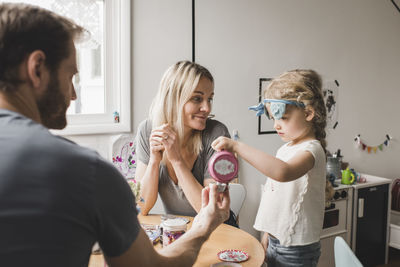 Parents and daughter having tea party in playroom