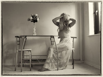 Rear view of young woman standing on chair