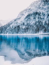 Scenic view of lake by snowcapped mountains against sky