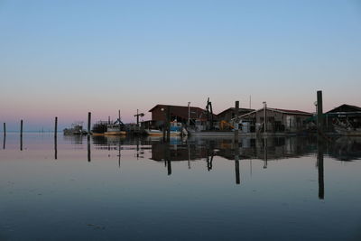 Reflection of stilt houses on sea against sky