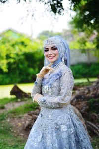 Portrait of smiling bride standing in park