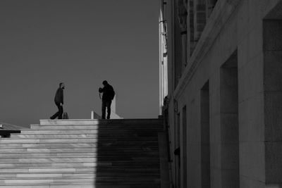 Silhouette men on staircase against sky