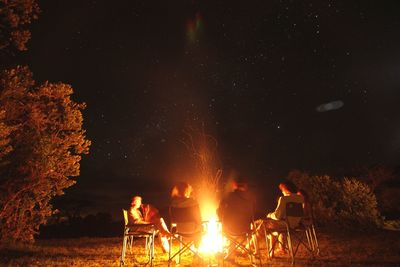 People sitting around campfire at night